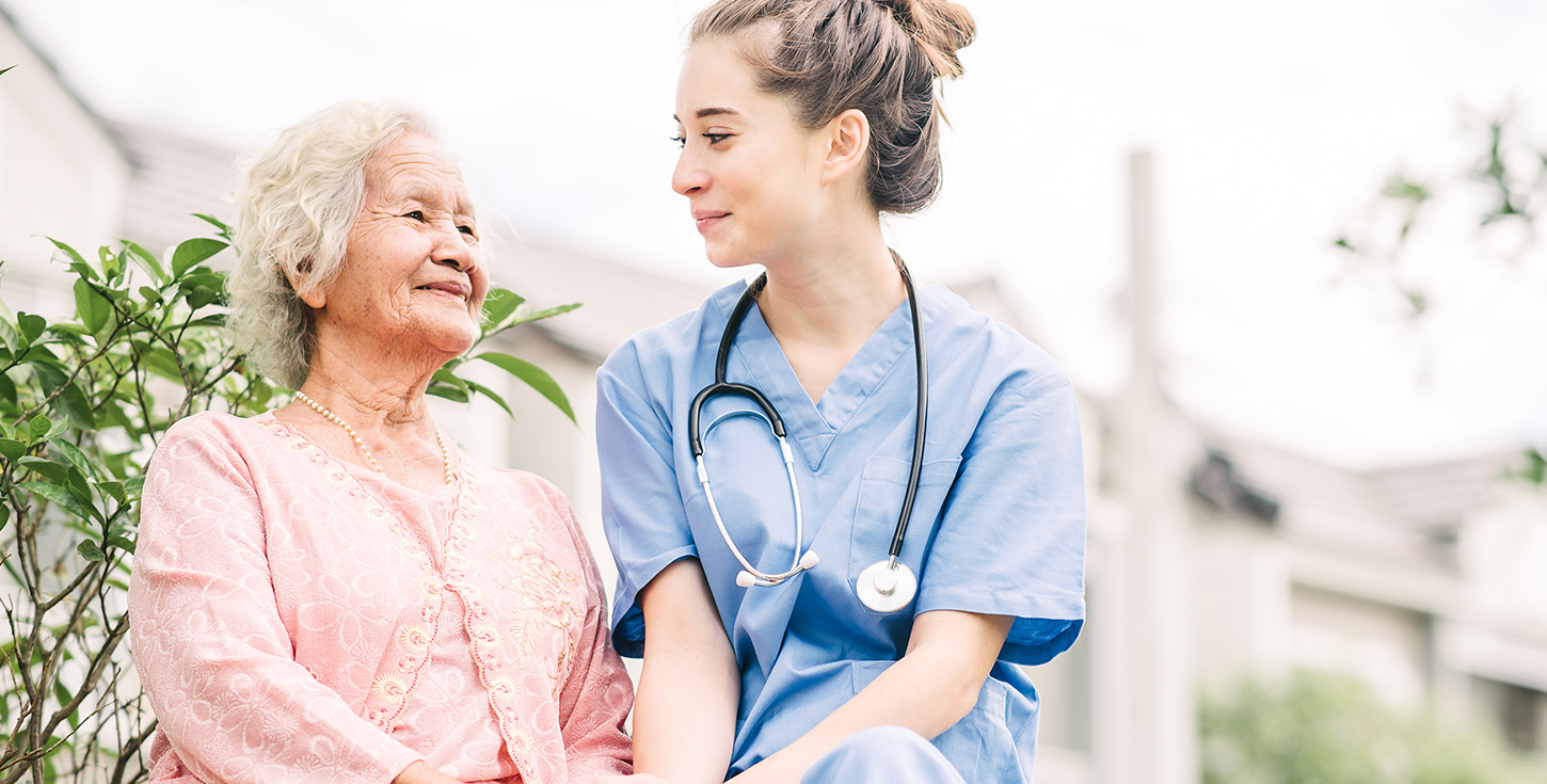 caregiver visiting with elderly asian woman