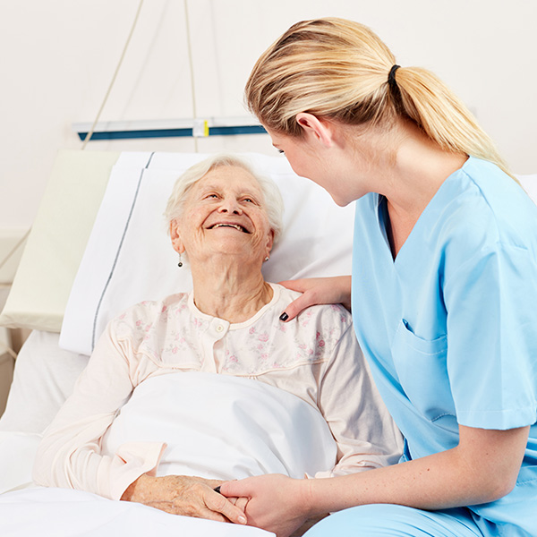 female nurse next to elderly woman on hospital bed