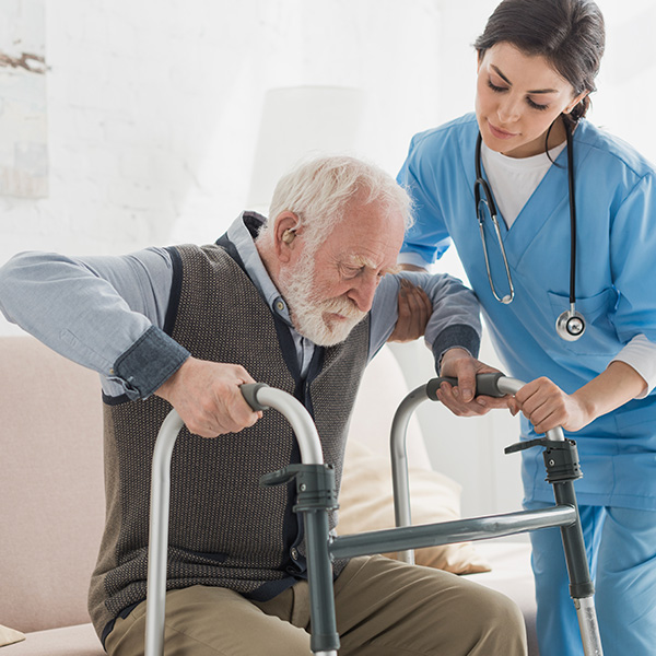 nurse helping elderly man with walker