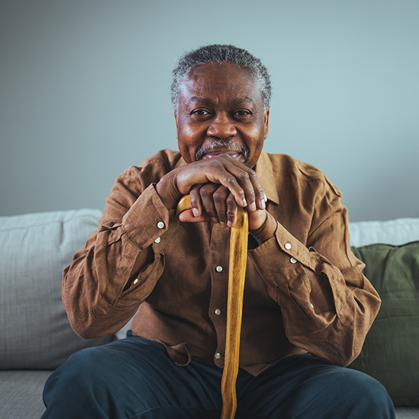 smiling senior black man with hands on cane